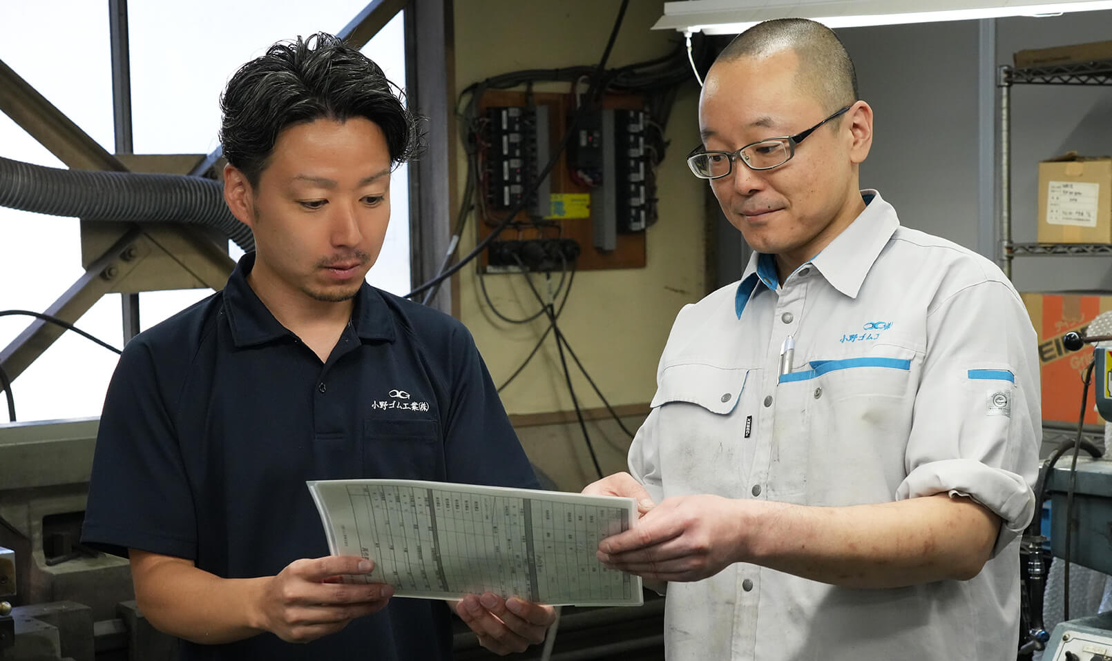 男性社員2名が資料を手に打ち合わせをする様子